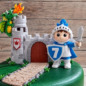 May include: A cake topper set featuring a gray stone castle with a red door, a green dragon breathing orange fire, and a knight in blue and white armor holding a gray sword and a blue shield with the white number 7, all on a green base.