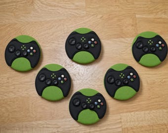 Op de afbeelding: Vijf ronde onderzetters met een zwart en groen ontwerp dat de lay-out van een videogamecontroller nabootst. Elke onderzetter heeft een zwart middengedeelte met knoppen en een groene, getextureerde rand in een verspreid patroon.
