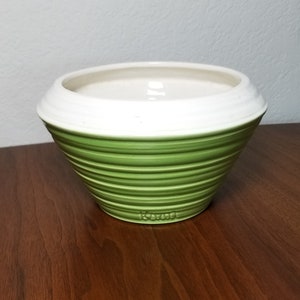 May include: A green and white ceramic planter with a ribbed design. The planter is made by Le Creuset.