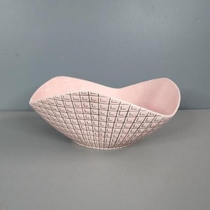 May include: A pink ceramic bowl with a geometric pattern. The bowl has a wavy edge and is perfect for serving snacks or fruit.
