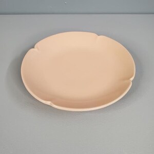 May include: A pale pink ceramic plate with a scalloped edge.