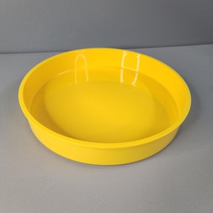 May include: A bright yellow round silicone baking pan with a smooth surface.