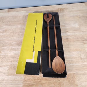 May include: A set of two wooden salad servers in a black box with a yellow label that reads "LAURIDS LØNBORG - COPENHAGEN DENMARK".