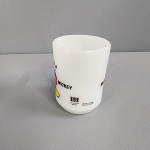 May include: White ceramic mug with a cartoon image of Mickey Mouse. The mug has the text "Mickey" and "Collector Series" on the side. The bottom of the mug has the text "Walt Disney Productions".