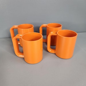 May include: Four orange plastic mugs with handles. The mugs are all the same size and shape.