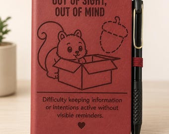 May include: A dark red notebook with a black pen attached by an elastic band. The cover features an engraved squirrel in a box, an acorn outline, and the text: OUT OF SIGHT, OUT OF MIND. Difficulty keeping information or intentions active without visible reminders.