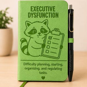 May include: A lime green notebook featuring a cartoon raccoon holding a clipboard with a checklist. The text reads "EXECUTIVE DYSFUNCTION" and "Difficulty planning, starting, organizing, and regulating tasks." A black pen is held by a green elastic loop.