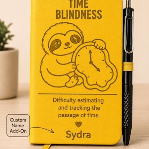 May include: A bright yellow notebook featuring a sloth holding a melting clock, with the text TIME BLINDNESS, Difficulty estimating and tracking the passage of time, and the name Sydra. A black pen is attached to the side of the notebook.