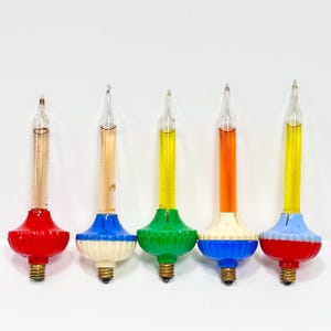 May include: Five vintage bubble light bulbs with clear glass tubes containing colored liquid. Each bulb features a decorative plastic base in red, blue, white, green, or light blue, with a standard metal screw-in base for electrical sockets.