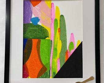May include: A framed artwork featuring a vertical abstract composition of bright orange, green, yellow, pink, and purple shapes. A solid black triangle occupies the bottom right corner. A small, gold-colored spoon is attached to the white matting.
