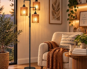 May include: A black metal floor lamp featuring three cylindrical shades wrapped in natural tan rope. The lamp has a tall, slender central pole with a circular base and three adjustable arms extending at different heights, each holding a light bulb.