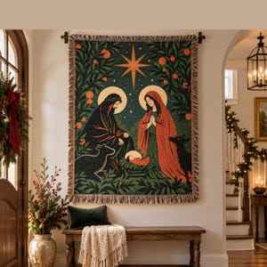 May include: A rectangular woven tapestry featuring a nativity scene with a central star, figures in dark and red robes, and a baby in a manger, surrounded by orange trees on a dark green background, finished with a fringed edge on all sides.