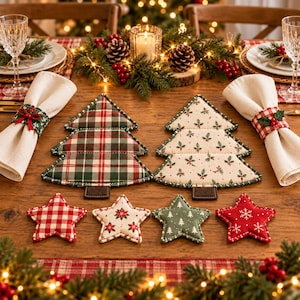 May include: Two quilted fabric Christmas tree placemats, one with a red and green plaid pattern and one with a holly leaf print, accompanied by four star-shaped fabric coasters in red gingham, floral, green tree, and red snowflake patterns.