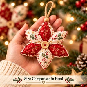 May include: A quilted fabric Christmas ornament shaped like a six-pointed star. The ornament features alternating red and cream panels with gold botanical patterns, red berries, and green pine needles. A wooden button sits in the center.