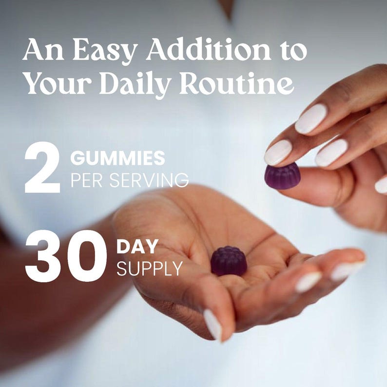 May include: Two small, dark purple, flower-shaped gummies. Text reads: An Easy Addition to Your Daily Routine, 2 GUMMIES PER SERVING, 30 DAY SUPPLY. The gummies have a textured, scalloped edge and a smooth, rounded top surface.