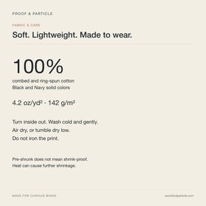 Op de afbeelding: Een stof- en onderhoudsinformatiekaart met de tekst Proof & Particle, Soft. Lightweight. Made to wear. 100% gekamd en ringgesponnen katoen in zwart en marineblauw, 4.2 oz/yd2, 142 g/m2, wasinstructies en een waarschuwing voor krimpen door hitte.