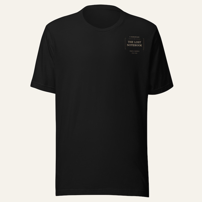 May include: A black short-sleeved t-shirt featuring a small rectangular graphic on the upper left chest. The graphic contains the text "THE LOST NOTEBOOK" in a serif font, enclosed within a thin border with decorative lines above and below.