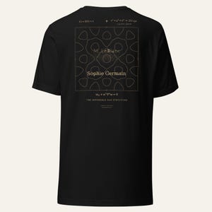 Pu&ograve; includere: Una t-shirt nera a maniche corte con una grafica dorata sul retro. Il design include equazioni matematiche, il testo M. LeBlanc, Sophie Germain e la frase THE IMPOSSIBLE HAS STRUCTURE centrata all'interno di una sottile cornice quadrata.