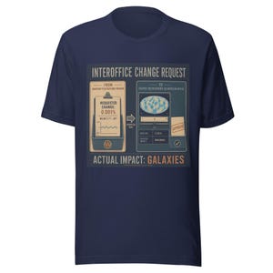 Op de afbeelding: Een marineblauw t-shirt met korte mouwen en een grafische print met de titel INTEROFFICE CHANGE REQUEST. Het ontwerp toont een bureaucratisch formulierproces tussen de Quantum Fluctuations Division en het Cosmic Background Calibration Office, eindigend met de tekst ACTUAL IMPACT: GALAXIES.
