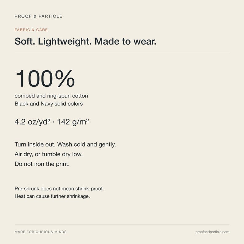 May include: A fabric and care information card with the text Proof & Particle, Soft. Lightweight. Made to wear. 100% combed and ring-spun cotton in black and navy, 4.2 oz/yd2, 142 g/m2, washing instructions, and a warning about heat-induced shrinkage.