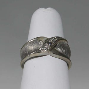 May include: A silver ring with a textured band and a row of small diamonds set in the center.