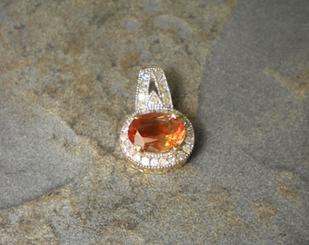 May include: A gold pendant with a large orange gemstone surrounded by a halo of smaller white gemstones.