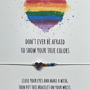 May include: A white card with a rainbow heart and the text "Don't ever be afraid to show your true colors". Below the heart is a silver heart charm bracelet with rainbow beads. The card also includes the text "Close your eyes and make a wish, then put this bracelet on your wrist. When the tiny thread wears through, that is when your wish comes true."