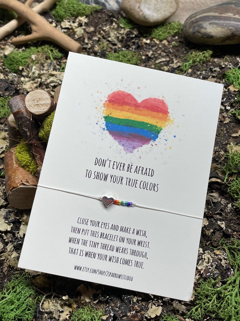 May include: A white card with a rainbow heart and the text "Don't ever be afraid to show your true colors".  The card also includes a rainbow string bracelet with a silver heart charm and the text "Close your eyes and make a wish, then put this bracelet on your wrist. When the tiny thread wears through, that is when your wish comes true. www.etsy.com/shop/2sparrowsstudio"