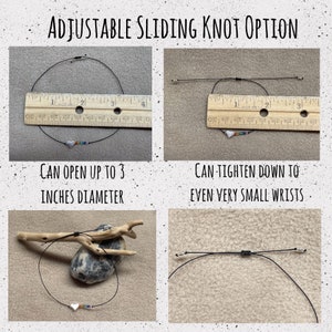 May include: A black cord bracelet with a sliding knot that can be adjusted to fit wrists up to 3 inches in diameter. The bracelet features a silver heart charm with rainbow beads. The bracelet is shown on a ruler and on a piece of driftwood.