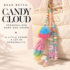 Può includere: Un ciondolo per borsa personalizzato con un pompon multicolore, una nappa color pastello e fili di perline che compongono il nome CLAUDIA. Il testo BEAD BETCH CANDY CLOUD PERSONALIZED NAME BAG CHARM A LITTLE CHARM. A LOT OF PERSONALITY. è visibile.