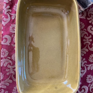 May include: A rectangular, olive green ceramic baking dish with a smooth, glossy finish.