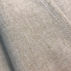 May include: Close-up of a beige fabric with a subtle woven texture. The fabric has a slight sheen and is folded over on itself.