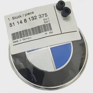 May include: A circular BMW emblem with a blue and white quartered design and a black outer ring, accompanied by two small black rubber grommets and a white packaging label featuring the part number 51 14 8 132 375 and a barcode.