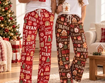 Puede incluir: Dos pantalones de estar por casa con motivos navideños. El pantalón rojo lleva estampado el nombre Ryan, hombres de jengibre, regalos y bastones de caramelo. El marrón lleva el nombre Olivia, casitas de jengibre y árboles.