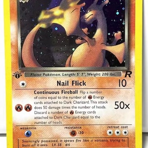 May include: A Dark Charizard trading card with 80 HP, featuring a holographic illustration of the dragon-like creature. The card displays the attacks Nail Flick and Continuous Fireball, with text detailing its length of 170 cm and weight of 91 kg.
