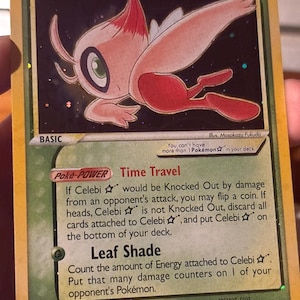 Puede incluir: Una carta coleccionable Pokémon Celebi Star holográfica con 60 HP. La carta presenta una ilustración de Celebi en rosa y blanco, el Poké-Power Time Travel y el ataque Leaf Shade. El texto incluye 'You can't have more than 1 Pokémon Star in your deck.'