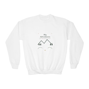 May include: A white long-sleeve sweatshirt featuring a central graphic with the text "Big Adventures" and "Carry a little inspiration everywhere." The design includes a black mountain outline, dark green pine trees, and two curved lines.