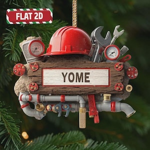 May include: A flat 2D hanging ornament featuring a red hard hat, a wrench, and pressure gauges mounted on a textured brown wooden board with the text YOME in the center. The design includes grey pipes, red valves, and metallic industrial tools.