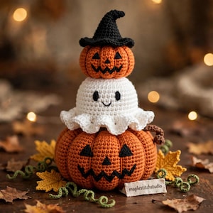 May include: A stacked crochet decoration featuring a large orange jack-o'-lantern at the base, a white ghost with a ruffled edge in the middle, and a small orange pumpkin wearing a black witch hat on top. A tag reads maplestitchstudio.