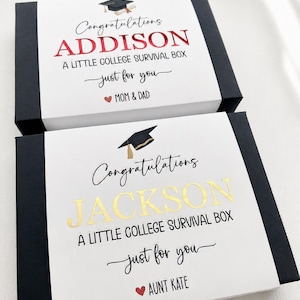 Op de afbeelding: Twee rechthoekige zwarte geschenkdozen met witte hoezen. De bovenste hoes bevat de tekst Congratulations ADDISON A LITTLE COLLEGE SURVIVAL BOX just for you MOM & DAD. De onderste hoes bevat de tekst Congratulations JACKSON A LITTLE COLLEGE SURVIVAL BOX just for you AUNT KATE.