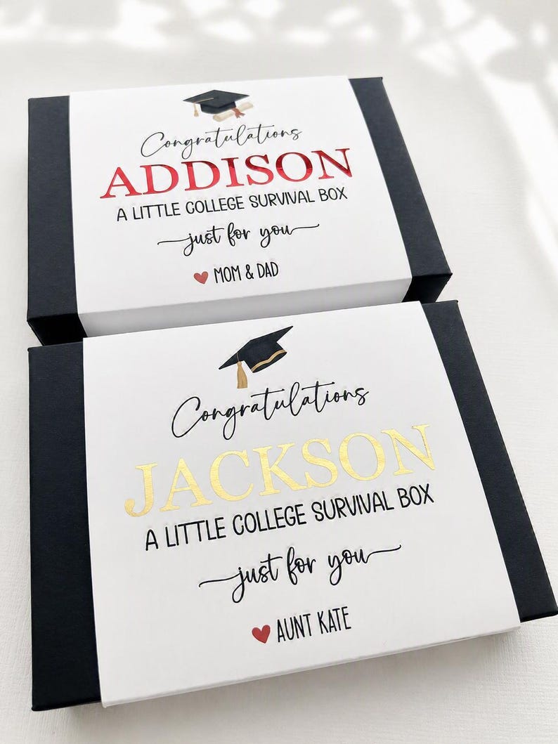 Op de afbeelding: Twee rechthoekige zwarte geschenkdozen met witte hoezen. De bovenste hoes bevat de tekst Congratulations ADDISON A LITTLE COLLEGE SURVIVAL BOX just for you MOM & DAD. De onderste hoes bevat de tekst Congratulations JACKSON A LITTLE COLLEGE SURVIVAL BOX just for you AUNT KATE.