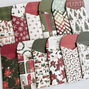 May include: A collection of Christmas-themed paper envelopes with various patterns. Designs include reindeer, snowflakes, Christmas trees, candy canes, and floral arrangements. The envelopes feature red, green, and white color schemes, perfect for holiday greetings.