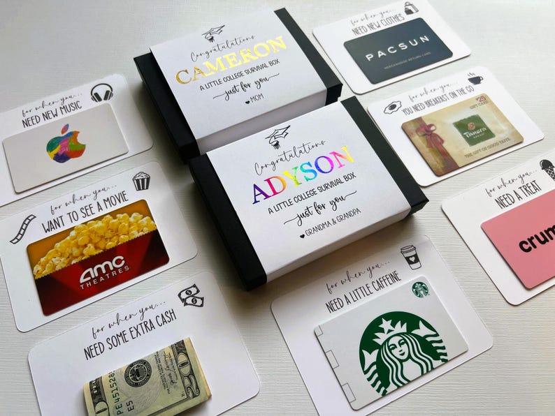 Op de afbeelding: Twee zwarte geschenkdozen met witte hoezen met de tekst Congratulations CAMERON A LITTLE COLLEGE SURVIVAL BOX en Congratulations ADYSON A LITTLE COLLEGE SURVIVAL BOX, omringd door cadeaubonnen voor Apple, PacSun, Panera, AMC, Crumbl en Starbucks.