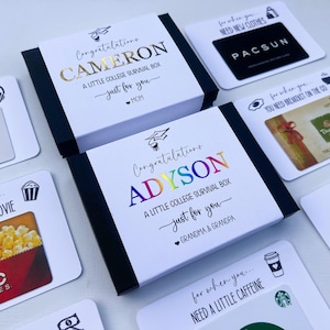 Op de afbeelding: Twee zwarte geschenkdozen met witte hoezen met de tekst Congratulations CAMERON A LITTLE COLLEGE SURVIVAL BOX en Congratulations ADYSON A LITTLE COLLEGE SURVIVAL BOX omringd door diverse cadeaubonnen met labels zoals NEED NEW CLOTHES.