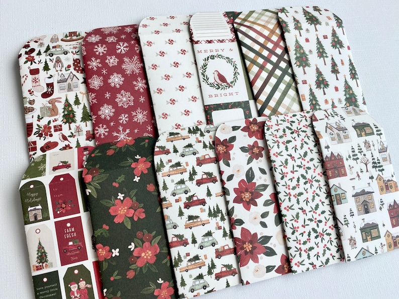 May include: A selection of Christmas-themed paper envelopes with diverse patterns. Designs include snowflakes, Christmas trees, floral arrangements, and holiday tags. The colour palette features red, green, and white.