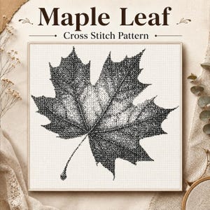 May include: A square cross stitch pattern featuring a detailed black and white maple leaf design on a grid background. The text "Maple Leaf" and "Cross Stitch Pattern" is printed in dark brown at the top of the square frame.