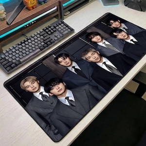 May include: A rectangular desk mat featuring a high-resolution print of five individuals wearing dark grey suits, white dress shirts, and ties. The individuals are arranged in a layered composition against a dark, paneled background.