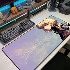 May include: A rectangular desk mat featuring an anime-style illustration of a blonde character with a serious expression. The background is a soft purple and white gradient with the text SOLO LEVELING printed in white capital letters.