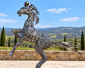 May include: A life-sized horse sculpture crafted from polished silver-toned metal. The figure is depicted in a rearing pose with intricate, swirling filigree cutouts throughout its body, mane, and tail, creating a hollow, openwork design.