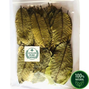 Pode incluir: Um saco de plástico transparente cheio de folhas secas castanhas de forma oval. Uma etiqueta branca quadrada apresenta o texto CEYLON PURE HERB dentro de uma borda circular de folhas verdes. Um emblema verde mostra 100% NATURAL com duas folhas.